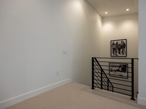 Your private upstairs landing offers a quiet spot to unwind, with modern railings and soft carpeting creating a peaceful transition between spaces.
