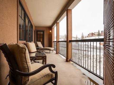 A covered balcony overlooks a winter landscape, offering a sheltered spot to take in snowy mountain views and seasonal scenery from comfortable lounge seating.