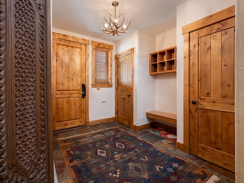 Step into your mountain retreat through this welcoming entryway, where rustic wood details and antler chandelier set the tone for your alpine escape.