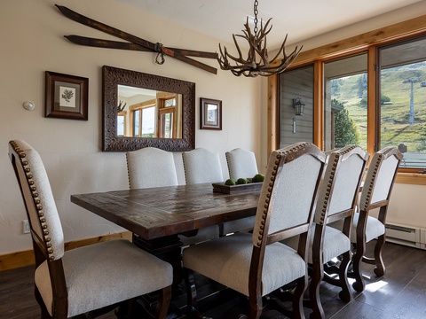 Gather around this handsome dining table where rustic mountain charm meets modern comfort, with natural light and scenic slopes framing your meals together.