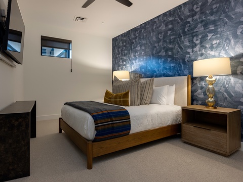 Slip into crisp linens beneath a striking accent wall, where warm lighting and thoughtfully curated details create your peaceful haven for restful nights.