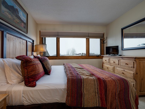 Sink into crisp white linens and colorful throws after a day of mountain adventures. Your cozy bedroom offers scenic views and rustic wood furnishings that feel like a home away from home.