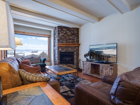 Cozy up in your living room with a crackling fireplace and mountain views, perfect for unwinding after a day of adventure.