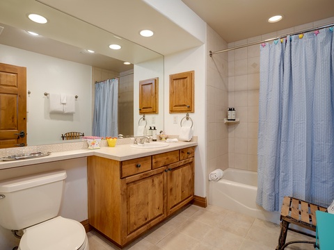 Your private bathroom features a spacious vanity with warm wood cabinetry, ample lighting, and a relaxing tub-shower combo—perfect for unwinding after a day exploring.