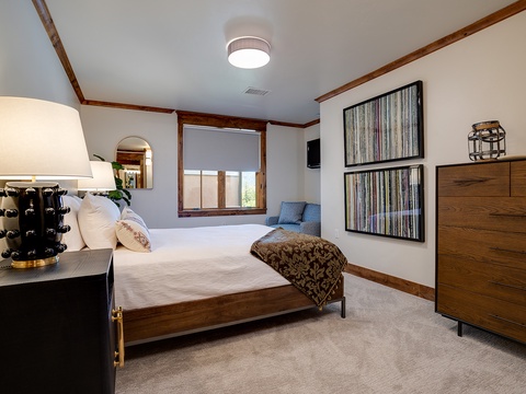 Sink into your plush bed beneath warm wood trim and modern art. Natural light spills through your window while the cozy sitting nook invites peaceful mornings with coffee.