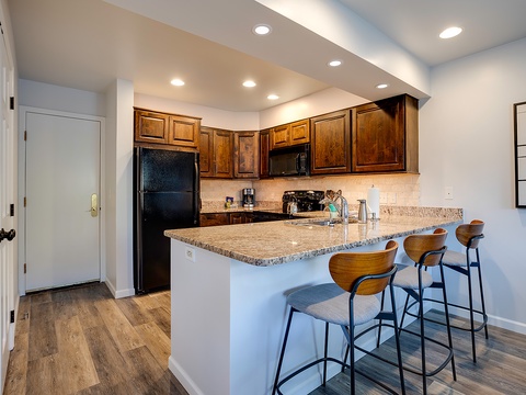 Your fully-equipped kitchen features granite countertops, rich wood cabinetry, and a breakfast bar with stylish seating—perfect for preparing meals and gathering with loved ones.