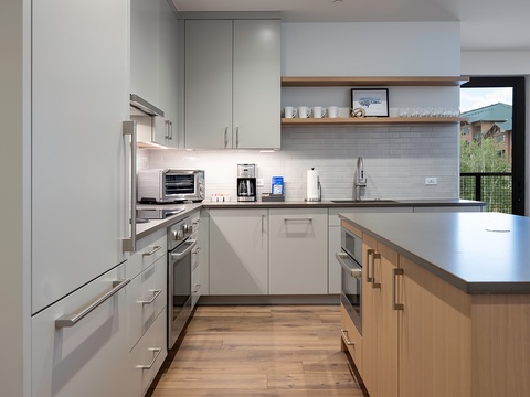 Your spacious, modern kitchen features stainless steel appliances, custom cabinetry, and warm wood accents—perfect for preparing meals while taking in mountain views through large windows.