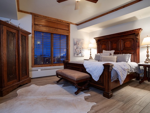 Sink into plush linens in this elegant bedroom, where warm wood tones and vaulted ceilings create your mountain retreat sanctuary after a day of adventure.