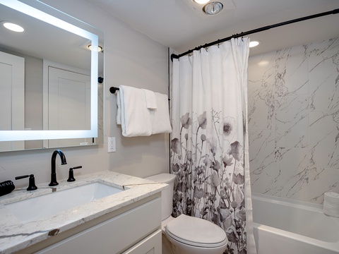 Step into your elegantly designed bathroom featuring a marble-veined shower, modern fixtures, and plush towels—your personal retreat to unwind after exploring all day.