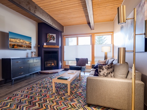 Sink into the plush sofa beside a glowing fireplace, where warm wood tones and modern style create your perfect retreat after a day of mountain adventures.