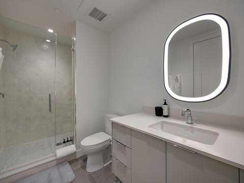 Sleek and modern, your bathroom offers a spa-like retreat with a spacious glass-enclosed shower, backlit mirror, and pristine vanity—perfect for refreshing after a day of adventure.