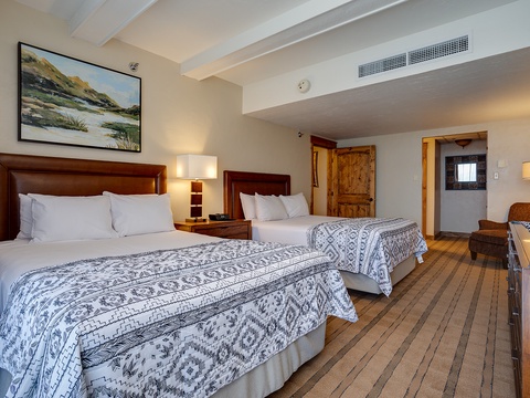 Settle into your spacious room with two plush beds dressed in soft linens, warm wood accents, and artwork that captures the natural beauty of the area.