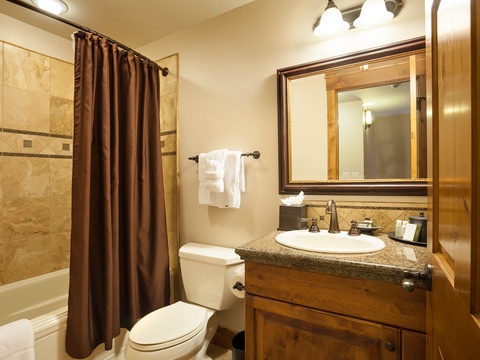 Your private bathroom features a tiled tub-shower combo, granite vanity, and fresh towels—everything you need to unwind after your mountain adventures.