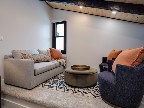 Sink into the plush sofas and let the warm, modern design wrap around you. Natural light from the window, exposed beams, and cozy textures invite you to truly unwind.