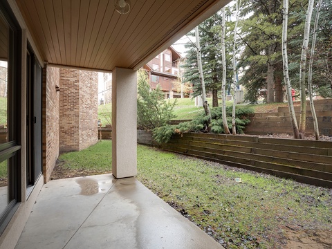 Your private covered patio overlooks a grassy yard with towering pines and aspens—perfect for morning coffee or quiet mountain moments.