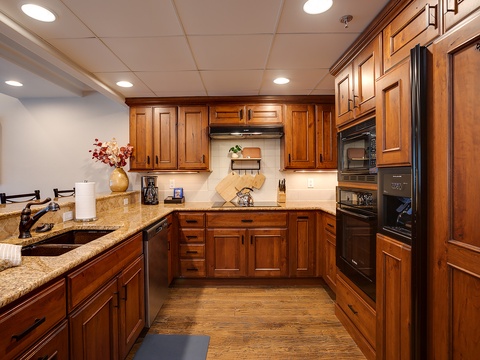 Step into your fully-equipped kitchen featuring rich wood cabinetry, granite countertops, and modern appliances—perfect for preparing family meals during your stay.