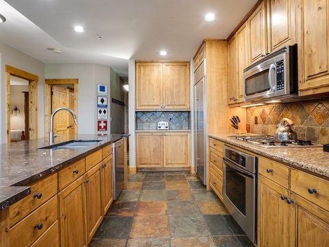 Your fully-equipped gourmet kitchen awaits, with stainless steel appliances, granite countertops, and warm wood cabinetry—perfect for preparing memorable meals together during your stay.