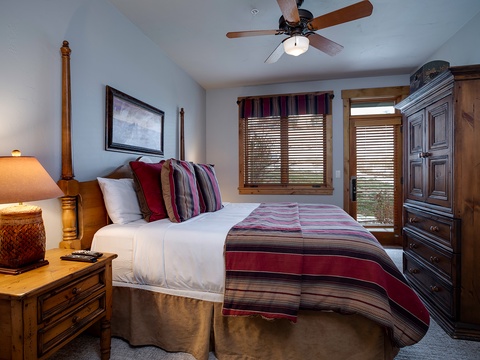 Settle into this cozy bedroom, where crisp linens and warm southwestern accents await your arrival. A ceiling fan whispers overhead while natural light filters through wooden blinds—your peaceful mountain retreat begins here.