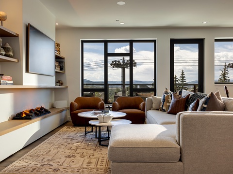 Sink into plush sofas and enjoy mountain views through floor-to-ceiling windows. The cozy fireplace adds warmth while you relax in this stylish, light-filled space.