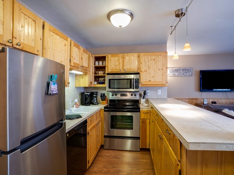 Your fully equipped kitchen features warm wood cabinetry, stainless steel appliances, and plenty of counter space for preparing meals together during your mountain getaway.