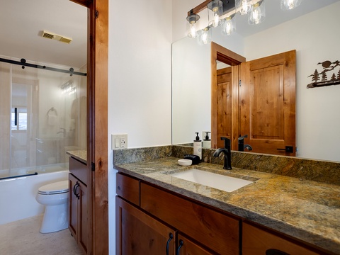 Freshen up in your private bathroom featuring a spacious granite vanity, modern fixtures, and a sleek glass shower. Warm wood accents and thoughtful lighting create a relaxing retreat after your day's adventures.