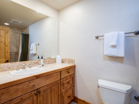 Your private bathroom features warm wood cabinetry, fresh towels, and a tiled shower—everything you need to refresh after a day of adventure.