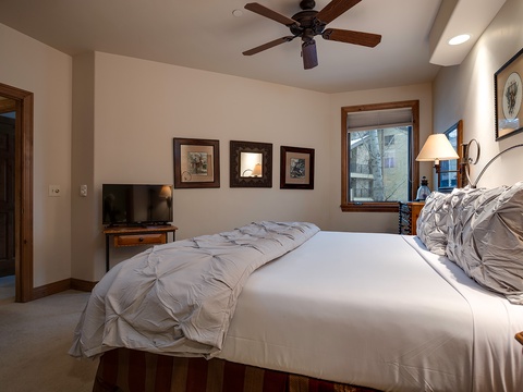 Sink into crisp white linens and let the ceiling fan's gentle breeze lull you to sleep. Your serene retreat features a cozy bed, mountain-view window, and thoughtful touches throughout.