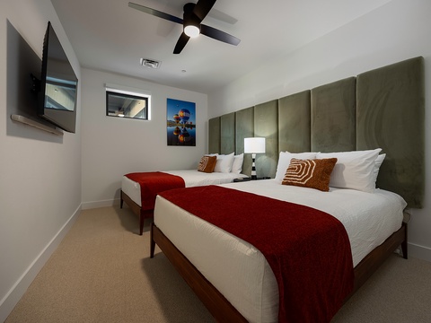 Settle into your plush bedroom with two queen beds dressed in crisp linens and rich red accents. A ceiling fan keeps you comfortable while you unwind with your favorite shows on the wall-mounted TV.