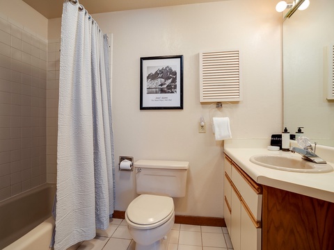 Your private bathroom features a tub-shower combo, fresh amenities, and warm lighting—everything you need to refresh after a day of adventure.