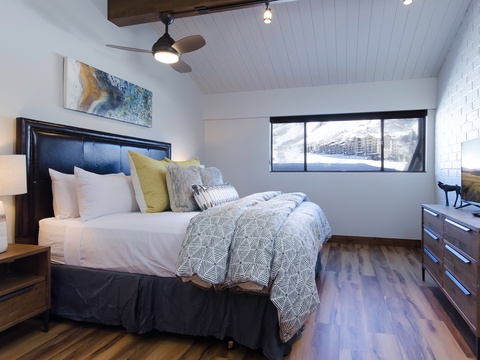 Sink into crisp linens and stylish comfort in your serene bedroom, where mountain views and modern touches like a ceiling fan and sleek TV make unwinding effortless.