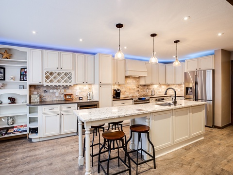 Gather around this spacious kitchen island with elegant white cabinetry, granite countertops, and modern appliances—perfect for whipping up your favorite meals and making memories.