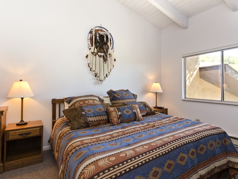 Cozy bedroom with Southwestern charm, featuring vaulted ceilings and natural light to frame your mornings. Curl up under patterned linens and feel right at home.