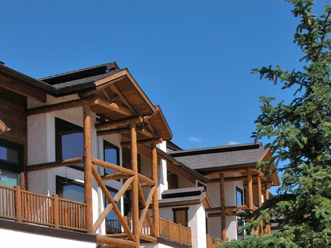 A charming mountain-style property featuring timber balconies and exposed wood beams set against a clear blue sky.