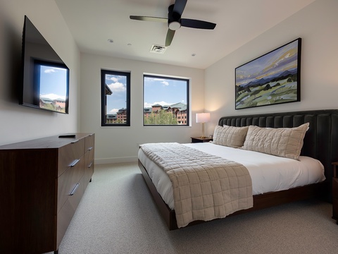Unwind in your bright, modern bedroom where mountains and sky frame your mornings. The plush bed and ceiling fan promise restful nights after exploring nearby attractions.