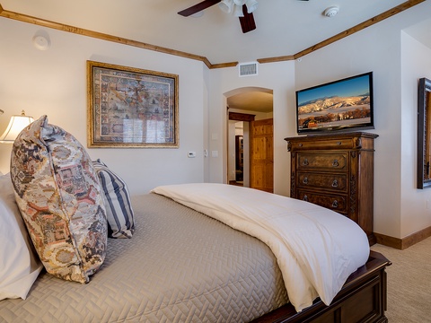 Sink into plush bedding beneath exposed wood beams in this serene bedroom, where mountain views greet you from the flat-screen TV and warm furnishings promise restful nights.