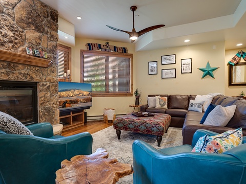 Unwind in your mountain-inspired living room with a cozy stone fireplace, plush seating, and vibrant pops of turquoise, where comfort meets charming Southwestern style.