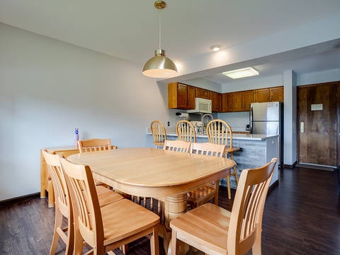 Step into your bright, open living area where a spacious dining table invites family meals and game nights. The full kitchen awaits your culinary adventures, complete with modern appliances and all the essentials.