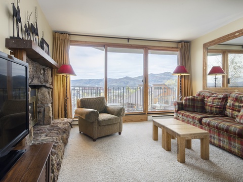 Unwind in your cozy living space with warm mountain views, a stone fireplace, and rustic charm perfect for gathering after a day of adventure.