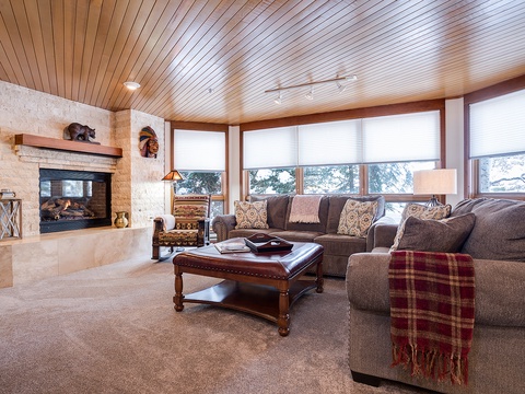 Sink into plush sofas by the crackling fireplace, where warm wood tones and mountain views create your perfect retreat after a day of adventure.
