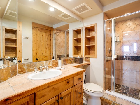 Step into your private bathroom with warm wood cabinetry, dual sinks, and a spacious walk-in shower—perfect for refreshing after a day of mountain adventures.