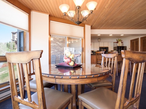 Gather around the warm wooden dining table where meals and memories come together, bathed in natural light from sweeping windows overlooking scenic mountain views.