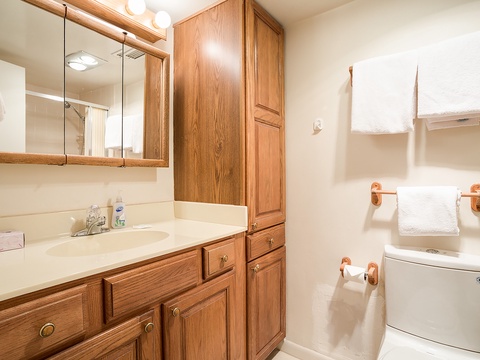 Your private bathroom features warm oak cabinetry, ample storage, and fresh linens ready for your stay.