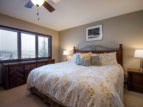 Drift off in your plush bed surrounded by warm tones and soft lighting. Wake to stunning mountain views through large windows, with modern comfort from the ceiling fan overhead.