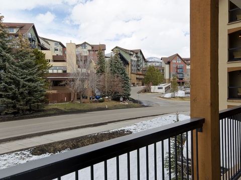 A tranquil neighborhood setting surrounded by evergreens and multi-story buildings, with patches of snow lingering in early spring. The area offers easy access to nearby amenities and trails.