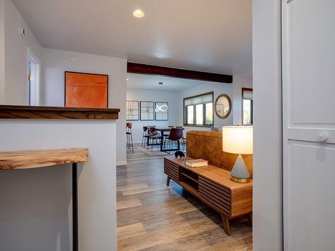 Step into your stylish retreat with exposed wood beams, modern artwork, and warm lighting that creates a welcoming ambiance throughout the open living and dining spaces.