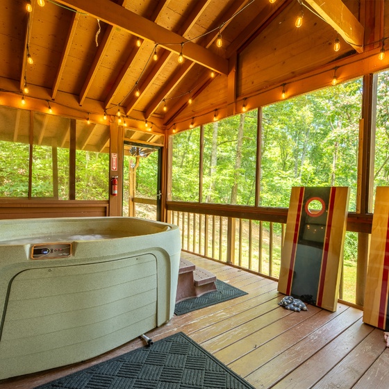 Soak in your private hot tub on the lovely porch while natural light and lush forest views surround you, with cornhole boards ready for friendly competition.