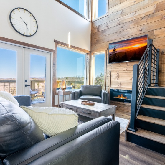 Unwind in your bright living space featuring warm wood walls, cozy fireplace, and comfortable seating perfect for relaxation.