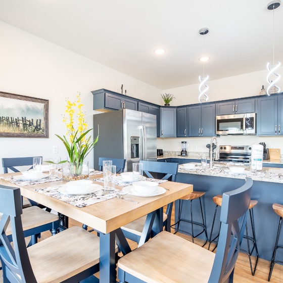 Your open-concept kitchen flows seamlessly with dining space, featuring sleek blue cabinetry and granite countertops perfect for cooking and gathering together.
