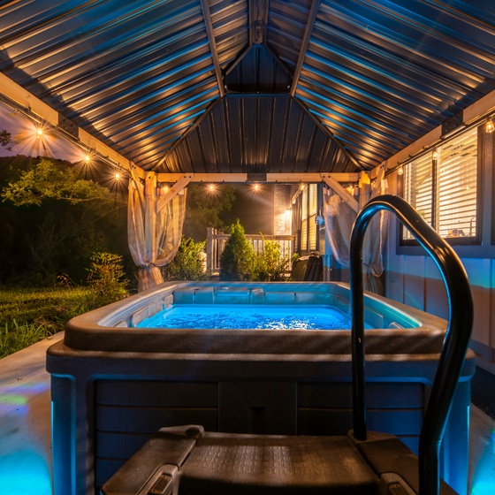 Your private hot tub awaits, glowing softly as evening settles in. Slip into the warm, bubbling water and unwind beneath twinkling lights, with the peaceful garden just beyond.