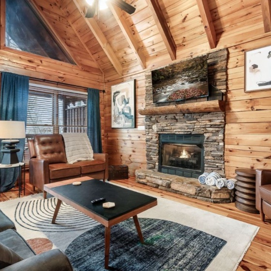 Cozy up by your stone fireplace in this warm cabin living room with leather chairs and rustic charm.